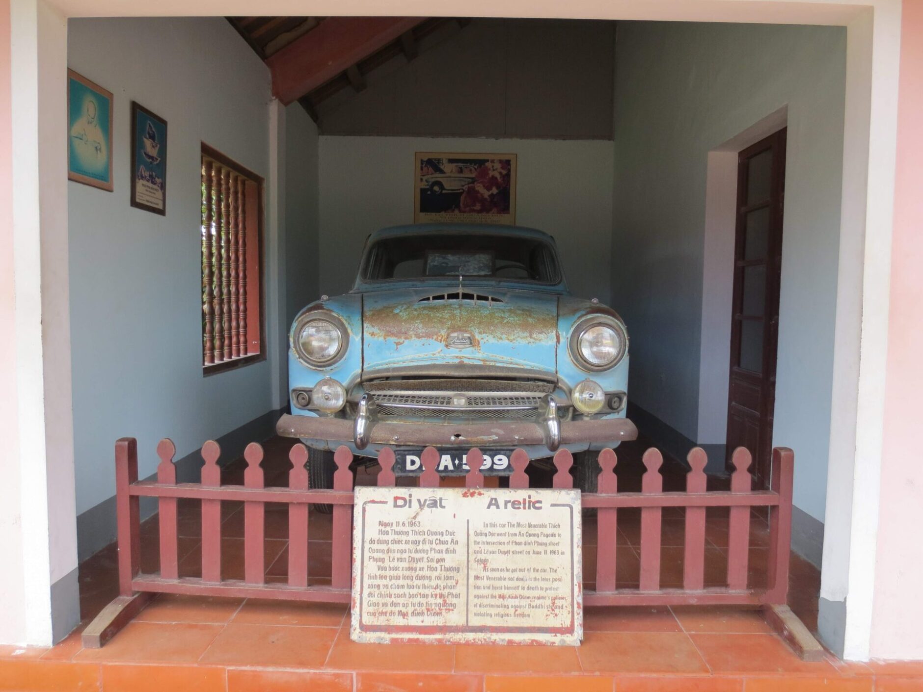 Vintage blue rusty car behind a red picket fence