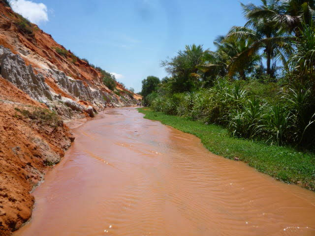 Muddy stream flowing through white sand cliffs of the Fairy Stream in Mui Ne, Vietnam