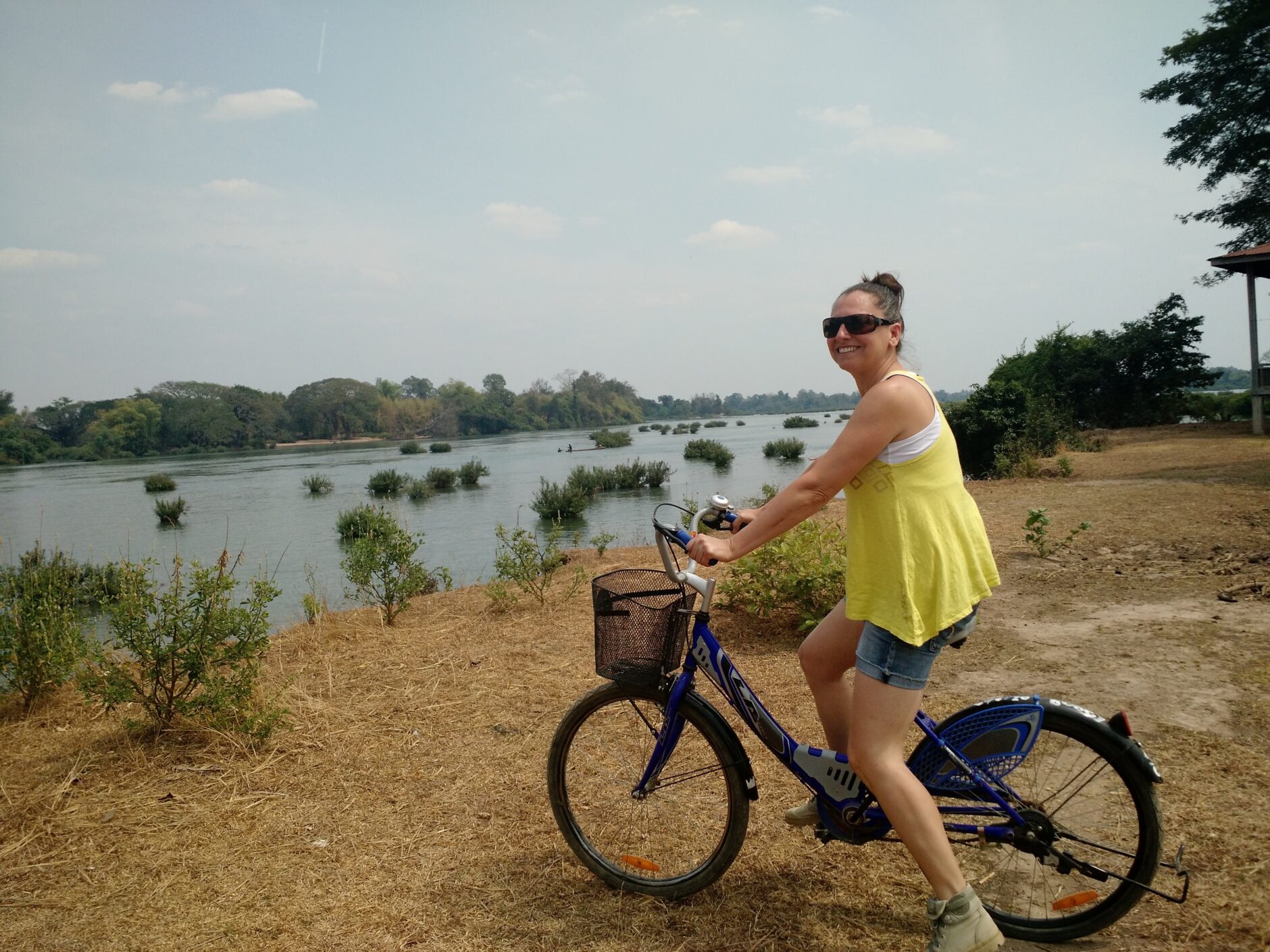 Girl in a yellow tank top on a bicycle by the Mekong River in Don Det, Laos