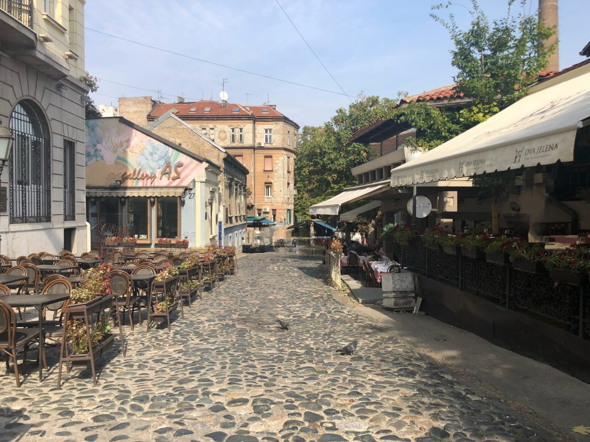 Wooden tables and chairs on a terrace of a restaurant located on a cobblestone lane