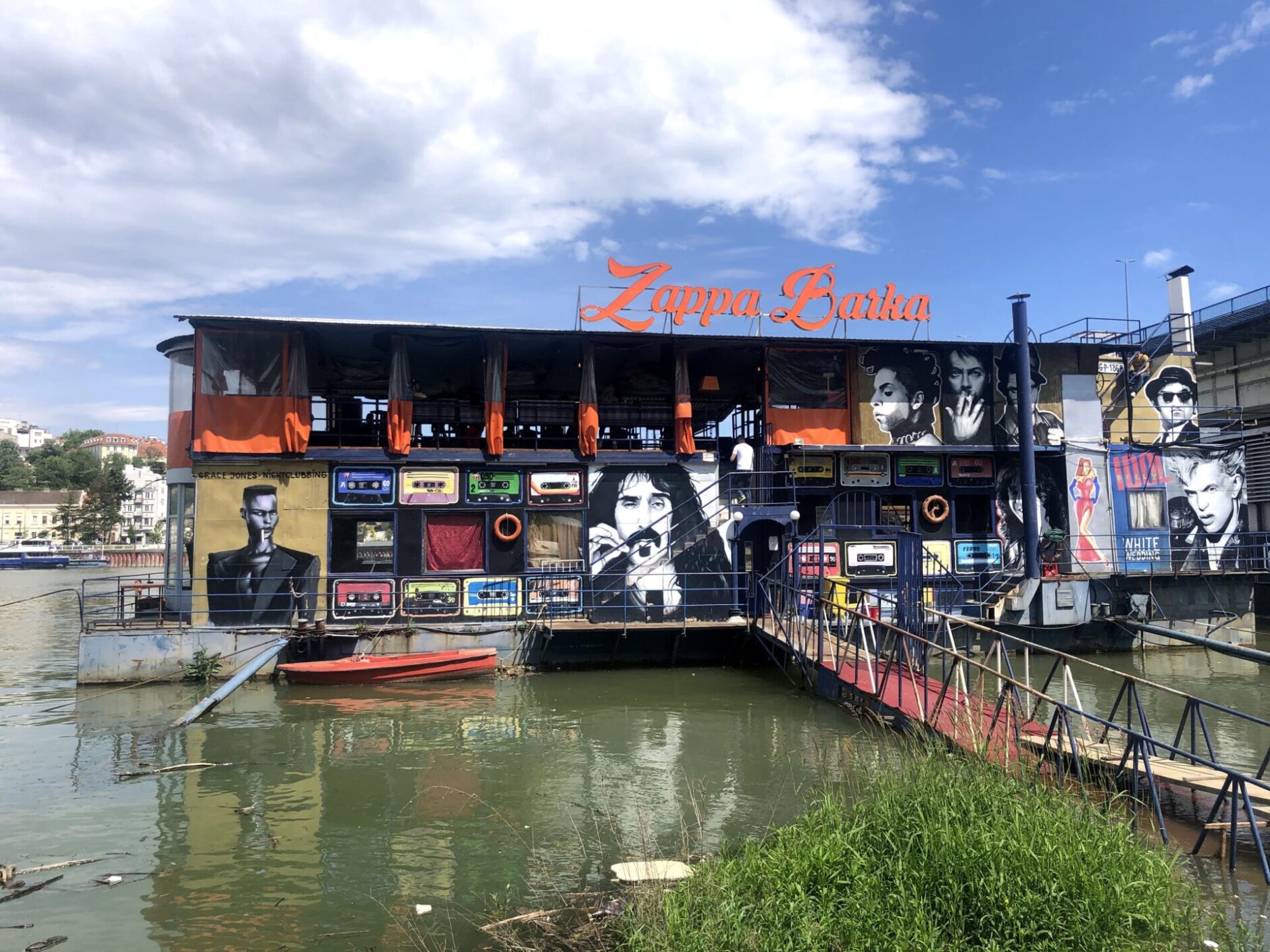 A floating bar called spavolvi on the Danube River with portraits of Frank Zappa, Prince, the Blues Brothers, Grace Jones and Billy Idol on the front