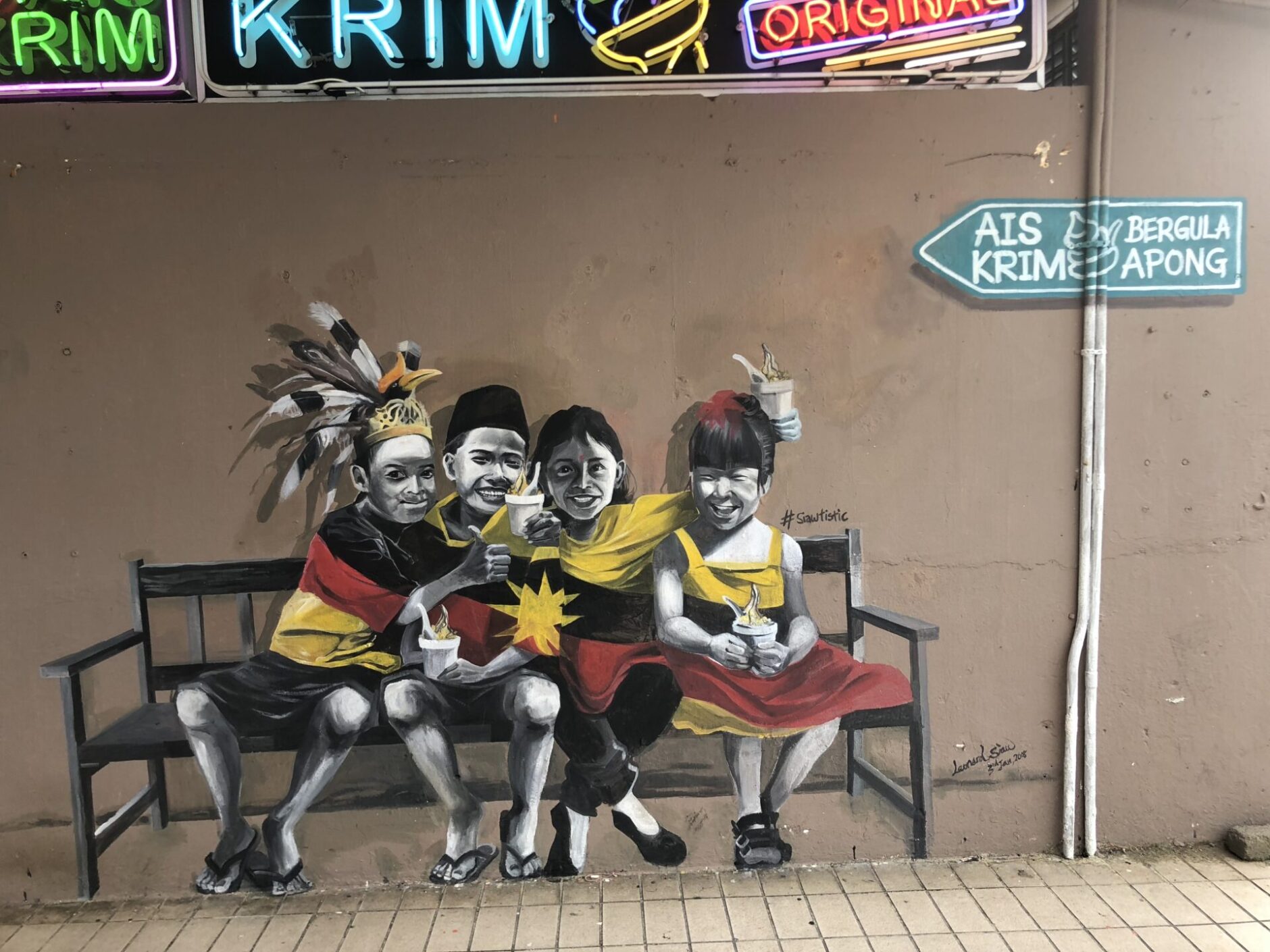 Mural art featuring four children of different ethnic backgrounds wrapped in a black, yellow and red flag