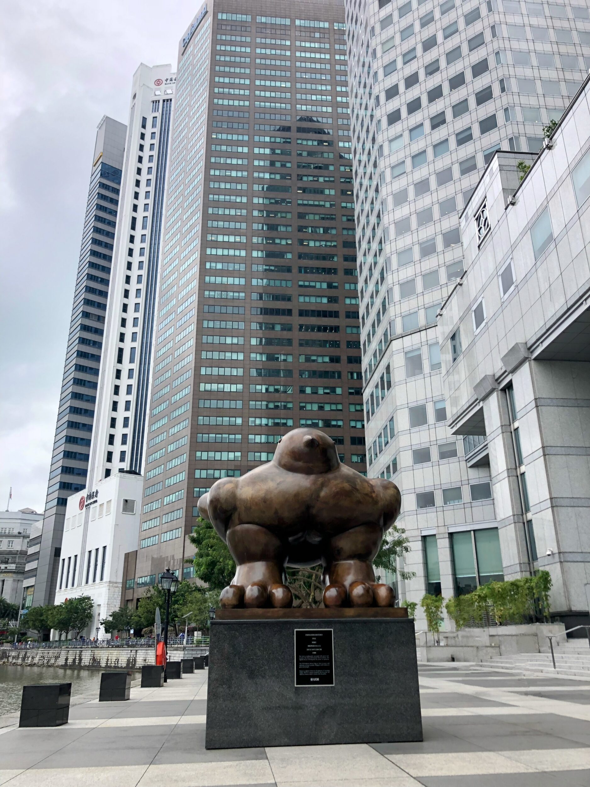 Large sculpture of a bronze bird in front of glossy skyscraper on the Riverfront Promenade in Singapore