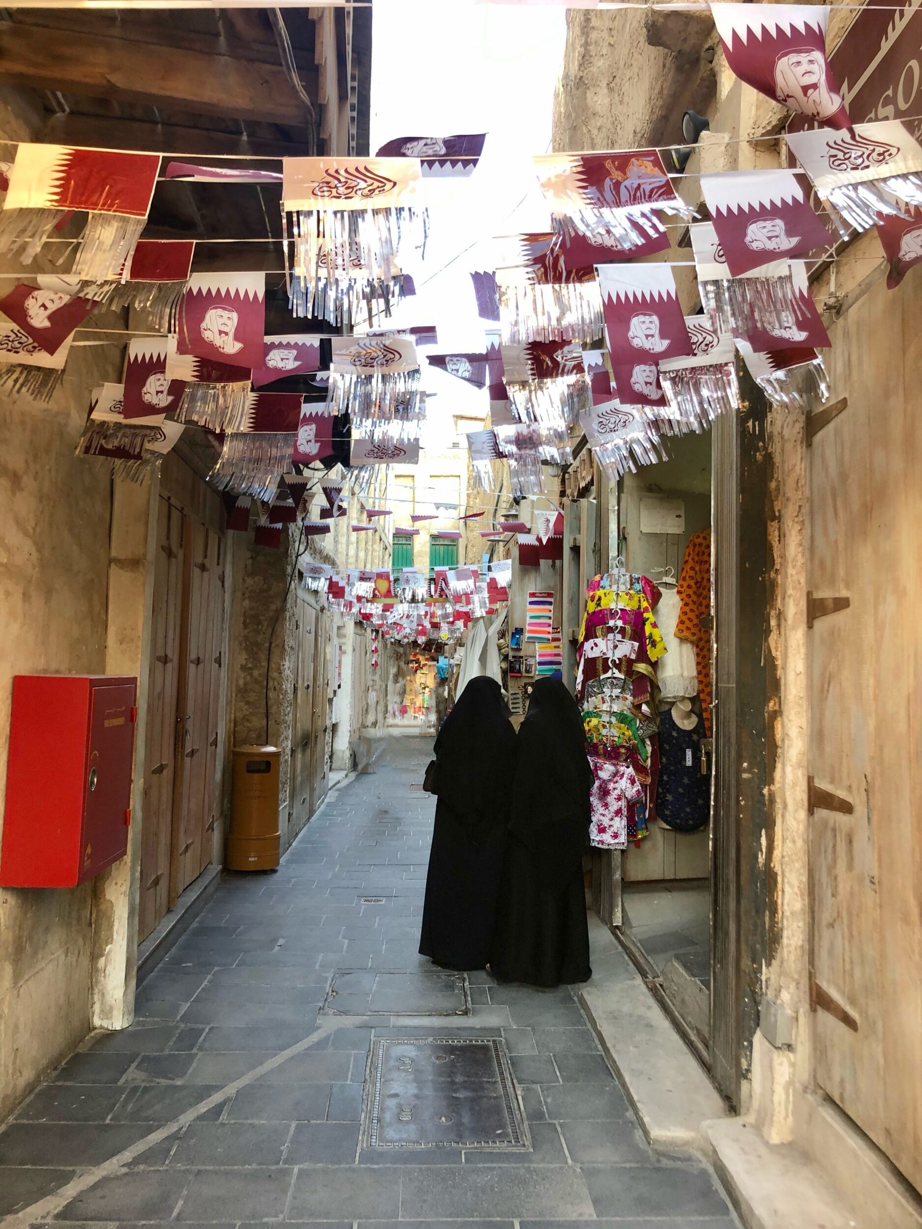 Qatari women wearing black abayas at a shop in a small alley of Souq Waqif in Doha, Qatar